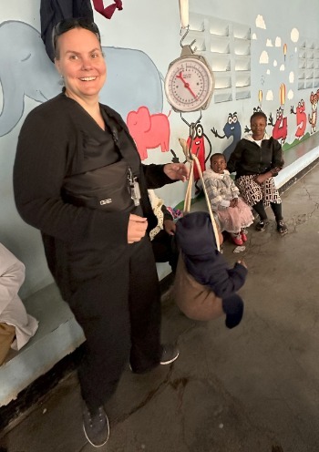 Author weighing a baby at a local hospital's Reproductive and Child Health unit in Tanzania. Photo taken with permission.